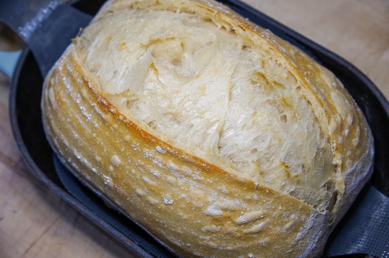 sourdough bread dough in an oval Dutch oven halfway through the bake
