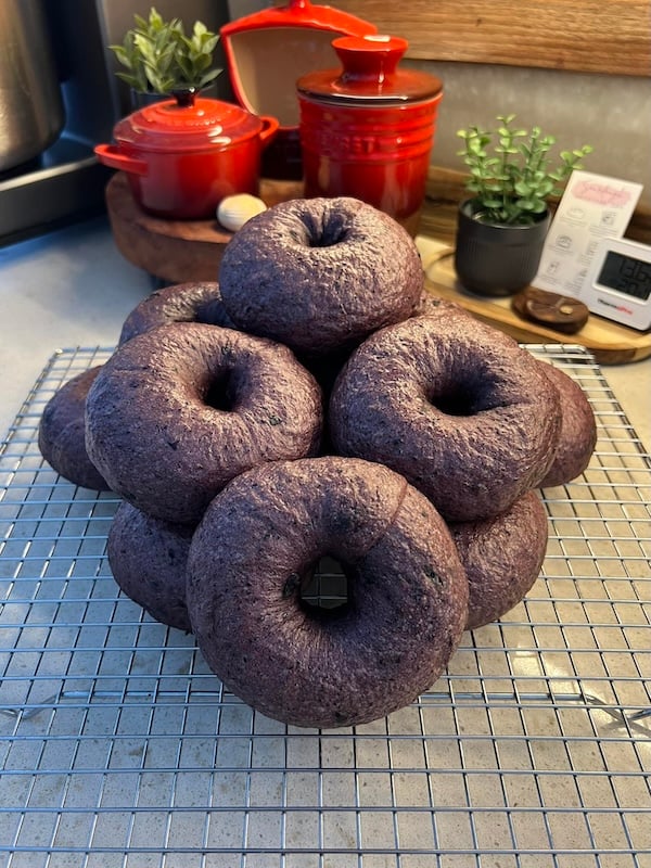 stack of finished blueberry bagels on a cooling rack in a kitchen
