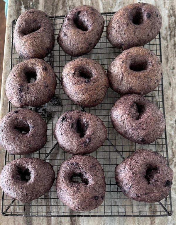 twelve baked blueberry bagels cooling on a wire rack