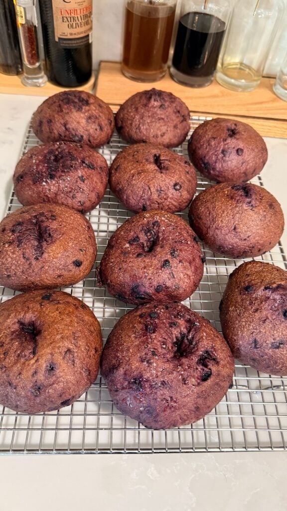 batch of baked blueberry bagels cooling on a wire rack