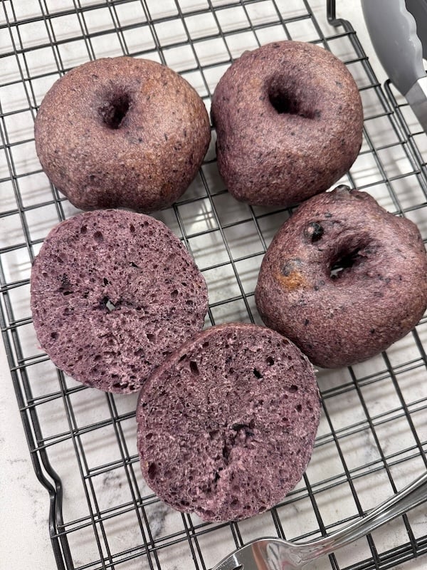 blueberry bagels on a cooling rack with two sliced halves showing the crumb