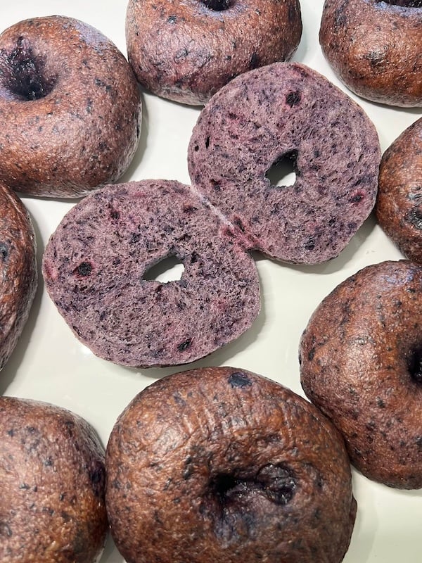blueberry bagels with two sliced halves showing the purple interior crumb