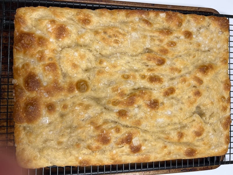 recipe tester focaccia showing a lightly golden top with shallow dimples