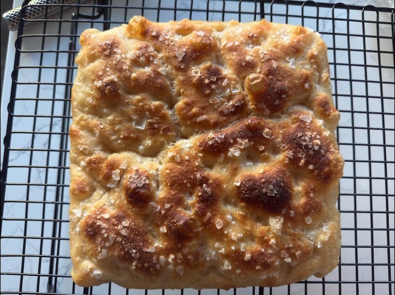 close-up of a recipe tester focaccia topped with flaky salt, showing a deeply browned, blistered crust