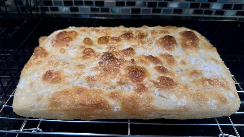Focaccia Recipe Tester loaf cooling on a wire rack, showing a blistered golden surface