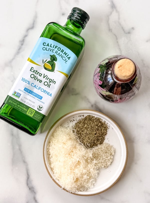 ingredients for dipping oil, including olive oil, balsamic vinegar, Parmesan, herbs, and coarse salt