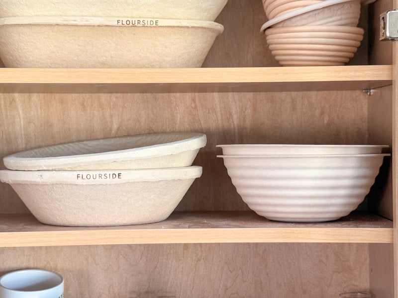 Flourside and brod and taylor bannetons stacked in wooden cabinet