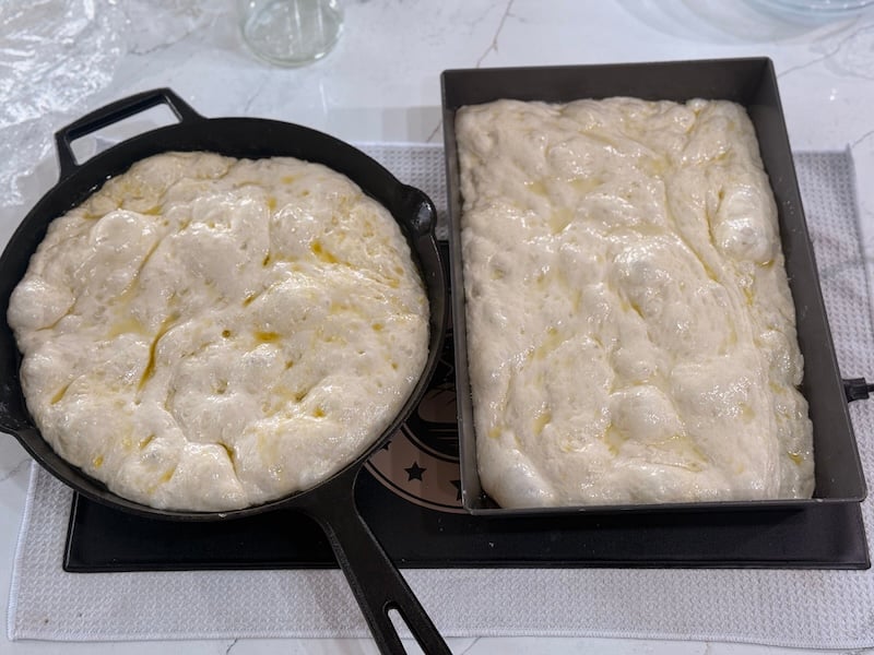 cast iron and lloyd pan with dimpled and oiled same day focaccia dough inside