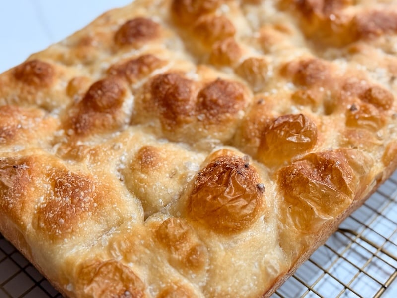 the top of same day sourdough focaccia showing a golden crispy crust with flaky sea salt