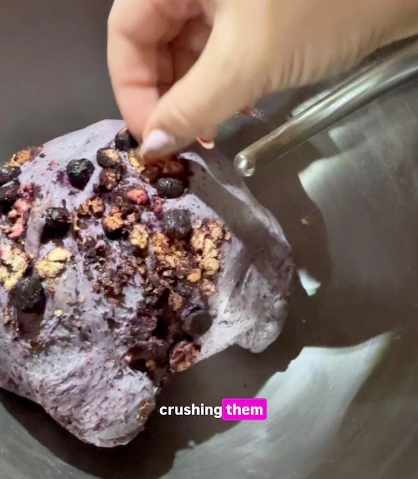 freeze-dried blueberries being crushed into wild blueberry bagel dough during kneading in a stand mixer bowl