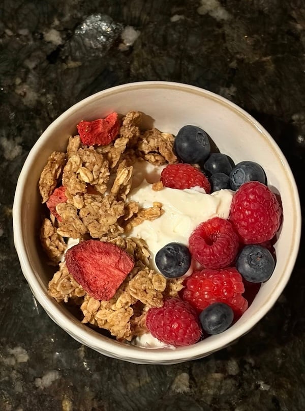 granola with fresh raspberries and blueberries on top of a bowl of yogurt