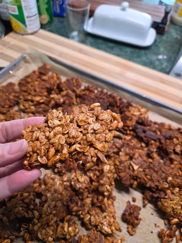 hand holding a granola cluster filled with oats, puffed rice cereal, and pumpkin seeds