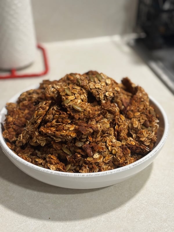 granola clusters with pumpkin seeds in large white bowl