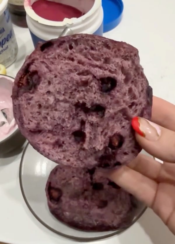 hand holding a sliced blueberry bagel with a darker purple crumb and visible blueberry pieces