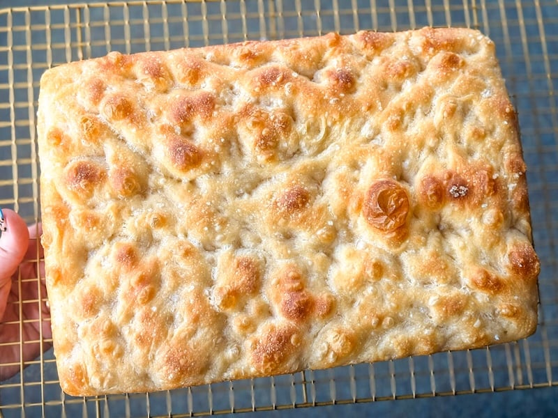 close-up of focaccia from recipe test 5, cooling on a rack, showing a blistered golden top and deep dimples