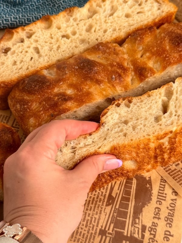 squishing a thick piece of airy browned sourdough focaccia