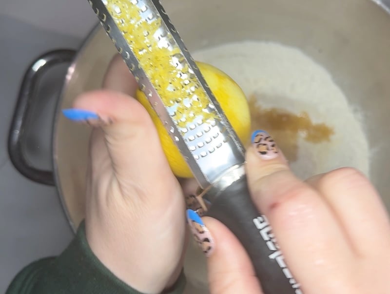 zesting a lemon over the bagel dough with a microplane before mixing