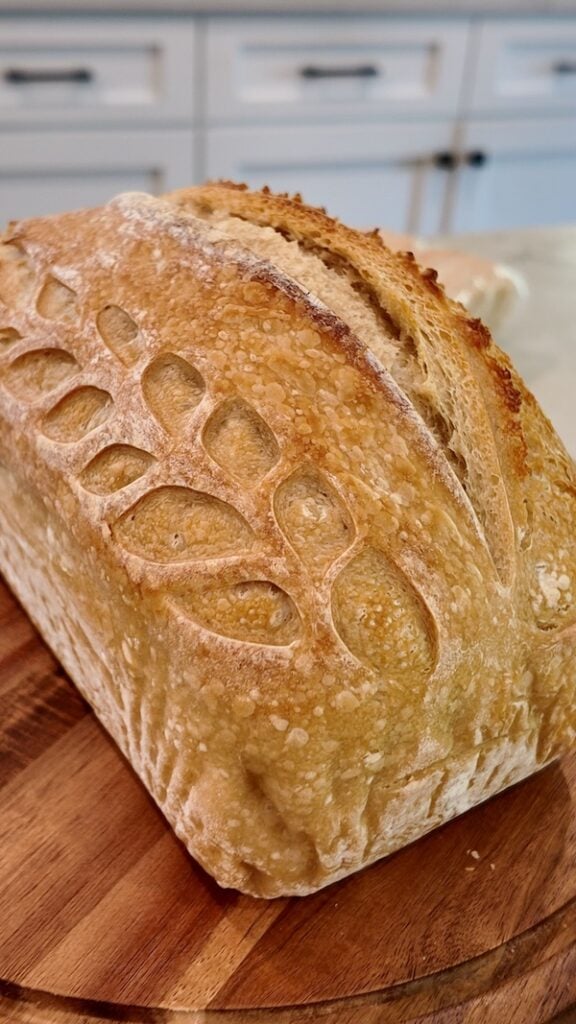 50% einkorn sourdough sandwich loaf with a decorative leaf score pattern, on a wooden board