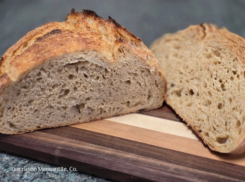 50% einkorn sourdough boule sliced in half, showing the crumb, on a cutting board