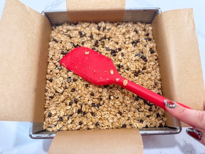 pressing the mixture into the pan with a spatula
