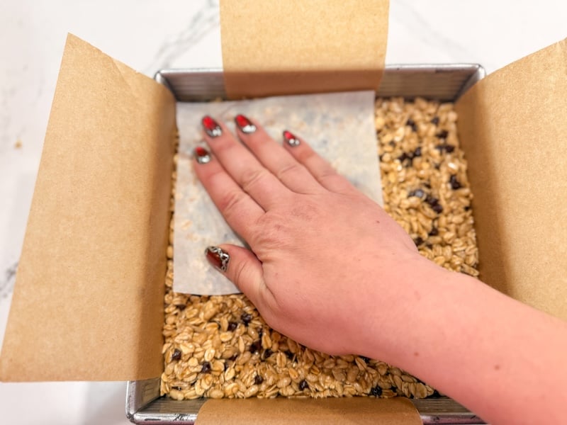 pressing the mixture into the pan with a spatula and parchment paper