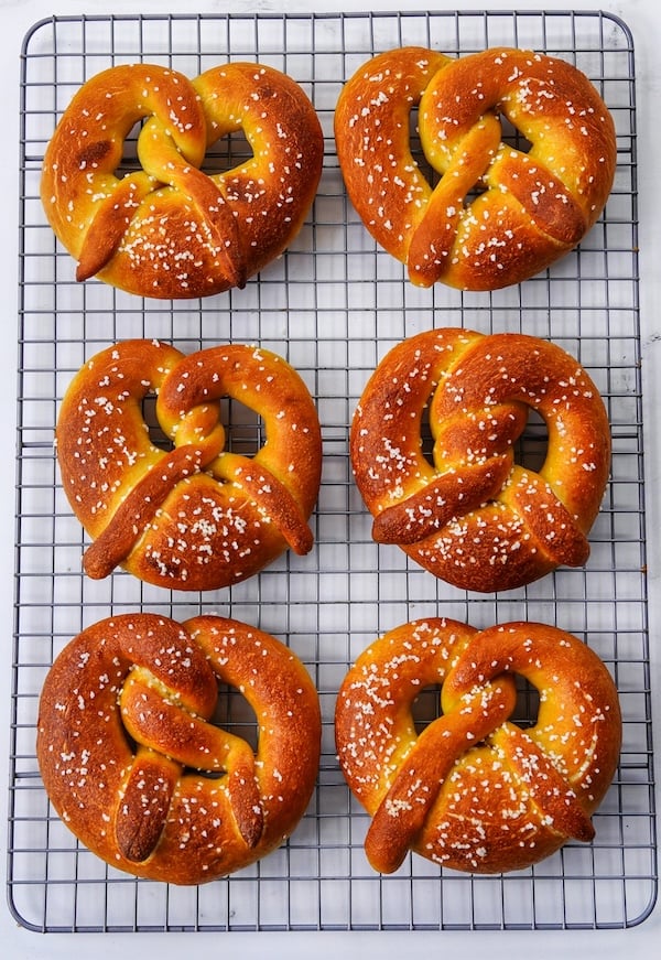 six soft sourdough pretzels cooling on a wire rack