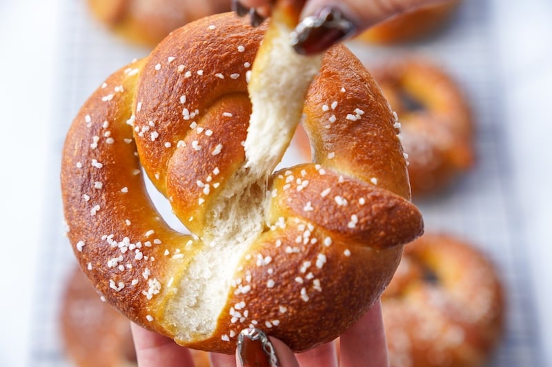 Soft sourdough pretzel being torn open to show the fluffy interior