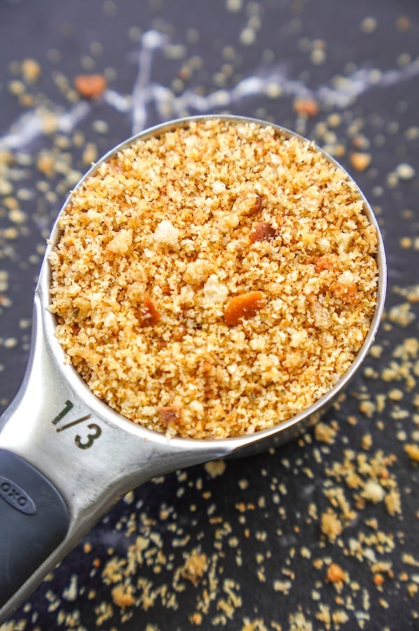 A heaping 1/3 cup measuring cup filled with golden, toasted sourdough Italian-style breadcrumbs