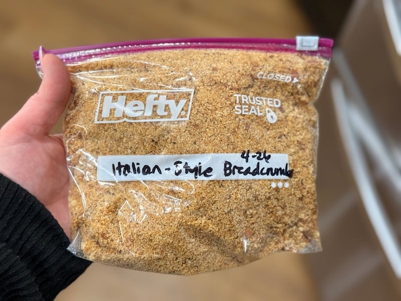 A hand holding a zip-top bag filled with sourdough Italian-style breadcrumbs.