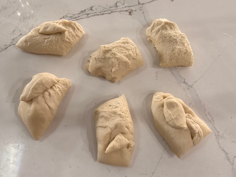 Six equal pieces of sourdough pretzel dough divided for shaping