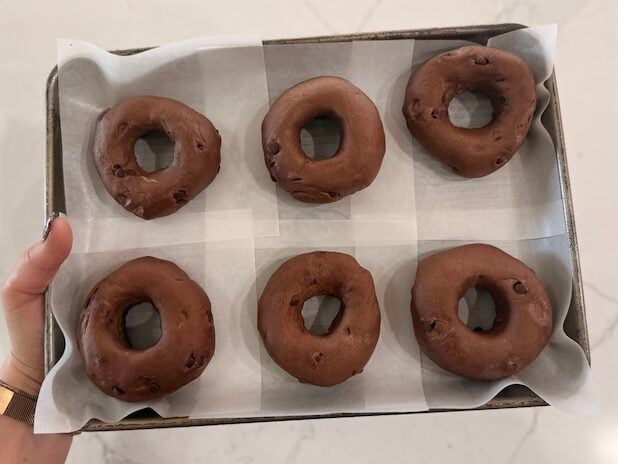 a sheet pan with shaped double chocolate sourdough bagels on parchment squares