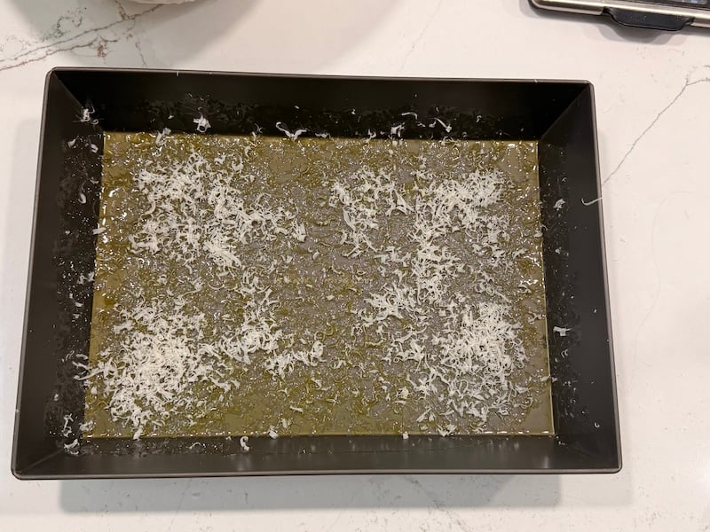 baking pan prepared to receive focaccia dough, with oive oil and grated parmesan on the bottom
