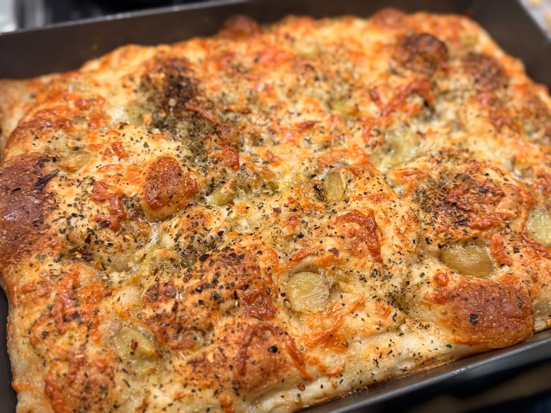golden baked cheese-topped sourdough focaccia with roasted garlic cloves