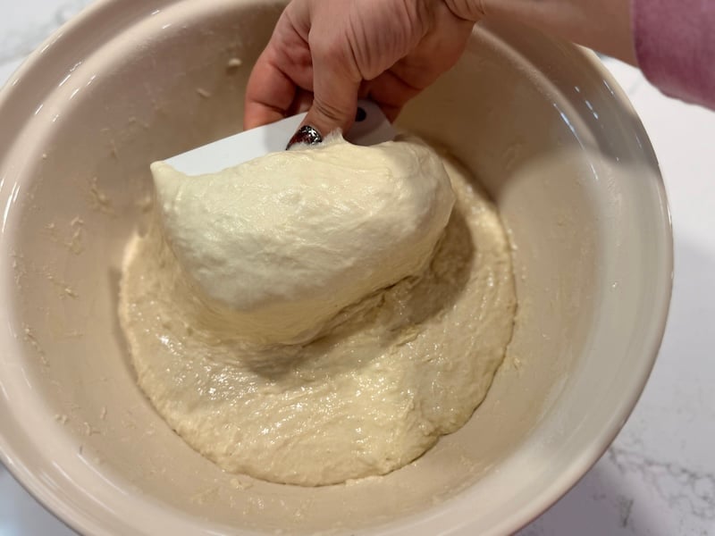 wet bowl scraper lifting sourdough focaccia dough during stretch and folds