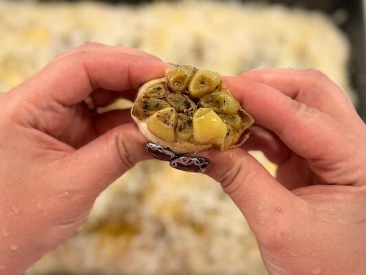soft roasted garlic cloves being squeezed from the head