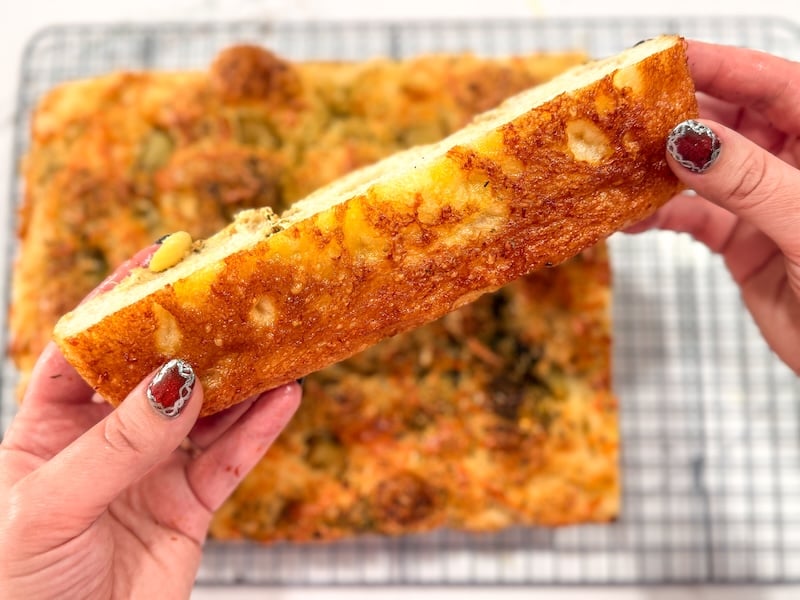 holding a slice of garlic and cheese focaccia showing the crisp golden bottom