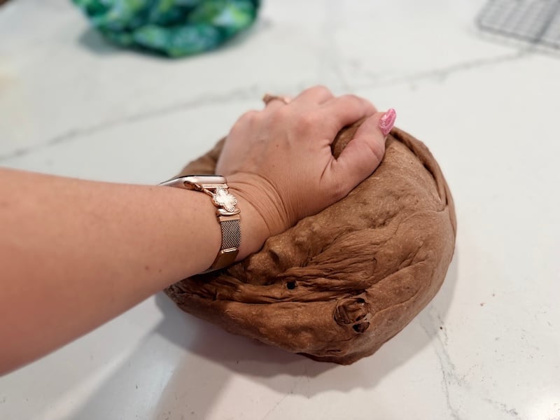 kneading the chocolate bagel dough on a countertop