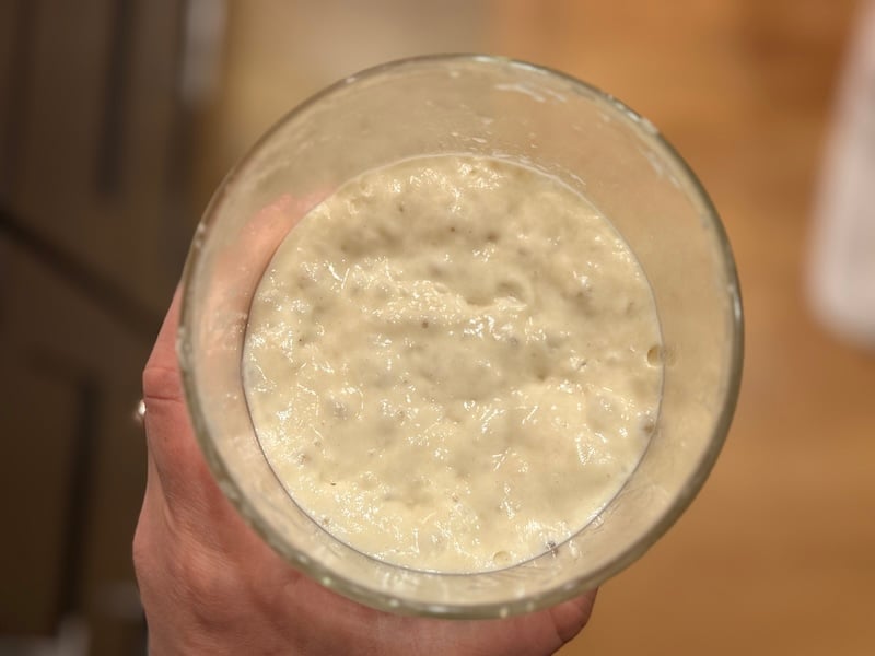 bubbly, peaked sourdough starter  in a glass jar