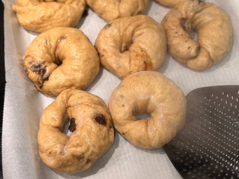 placing boiled bagel onto new parchment lined sheet tray