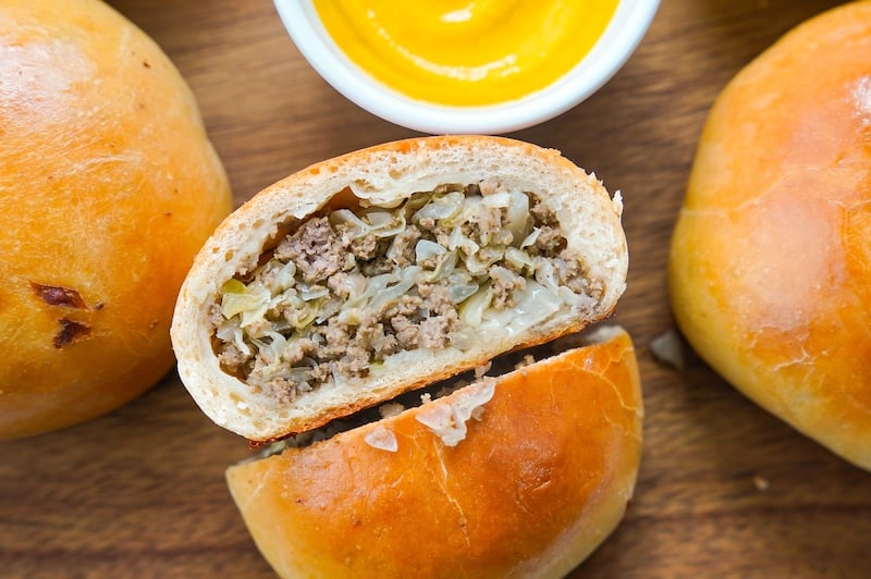 cabbage and beef stuffed sourdough runza on a platter with mustard