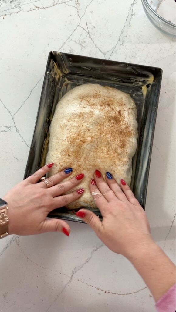 Gently press and stretch focaccia to fill the pan