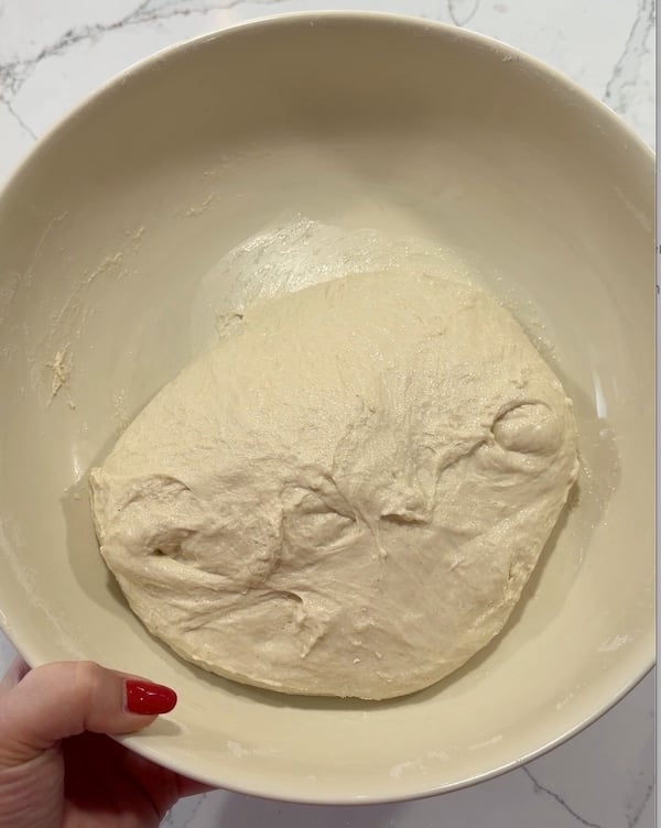 focaccia dough after the first round of coil folds, still loose and uneven in the bowl