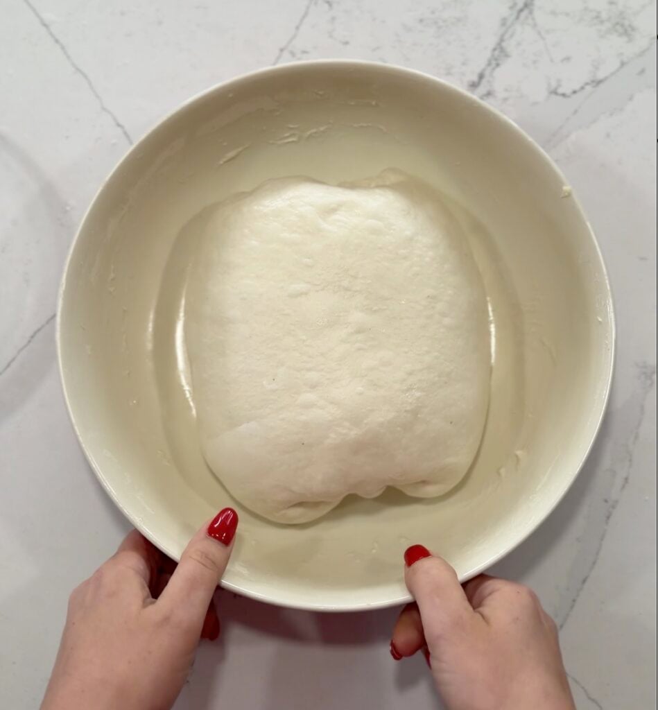 focaccia dough after the fourth round of coil folds, smooth and holding a defined shape in the bowl