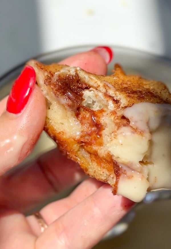 holding a gooey slice of cinnamon roll focaccia