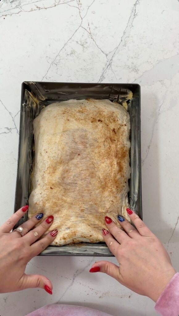 pressing edges of the dough to fully fill the pan