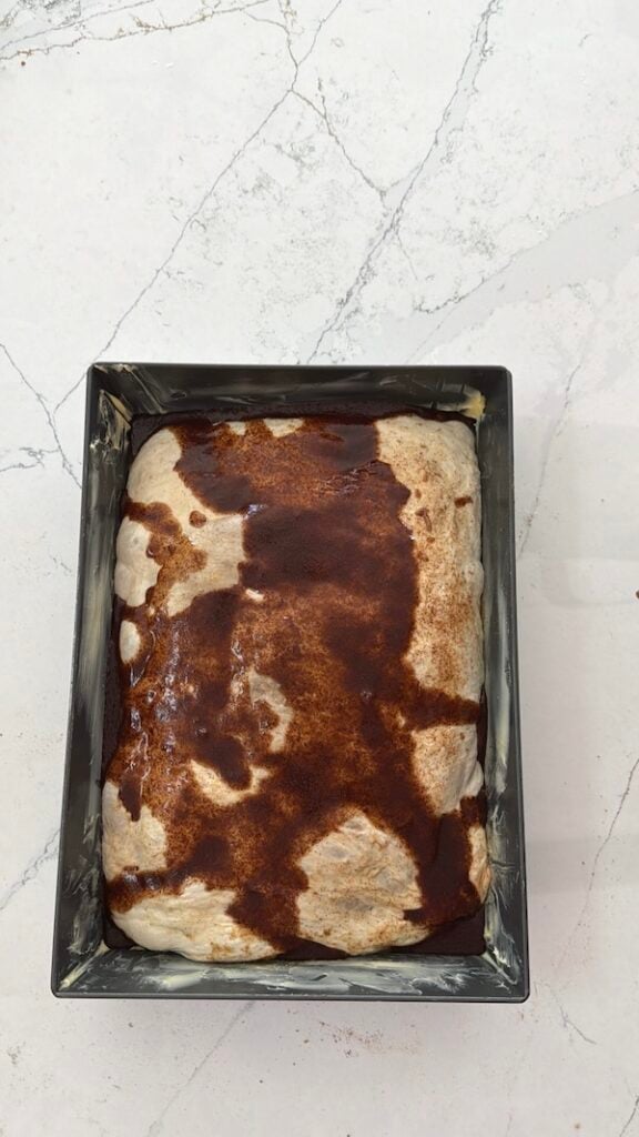 wet cinnamon butter mixture poured onto focaccia dough