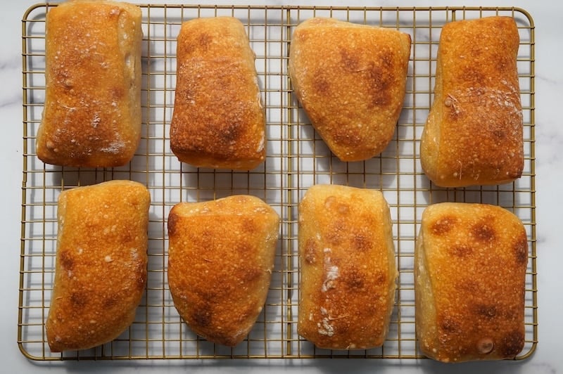 eight sourdough ciabatta rolls on a cooling rack