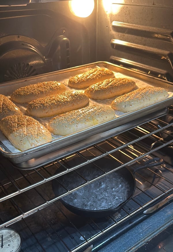rolls in the oven on top of an inverted sheet pan and a cast iron pan on the bottom rack