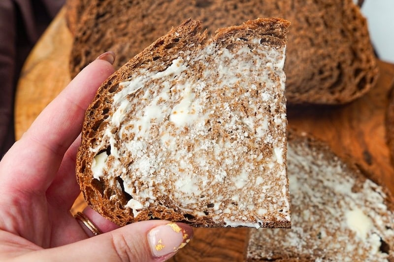 holding a piece of buttered brown bread