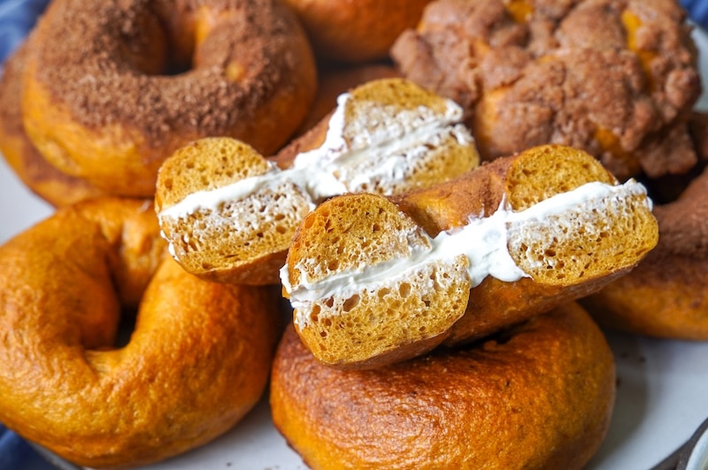 pumpkin bagel sliced in half filled with cream cheese